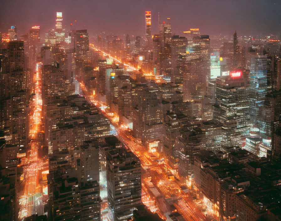 Nighttime cityscape with illuminated streets and high-rise buildings.