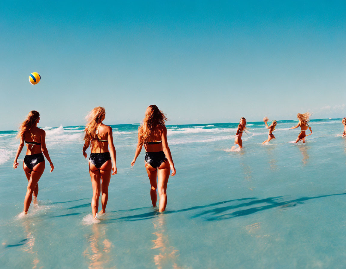 People playing beach ball in shallow waters under sunny sky