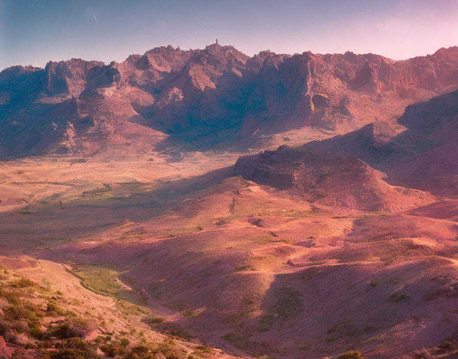 Rugged mountain range under soft pink sky