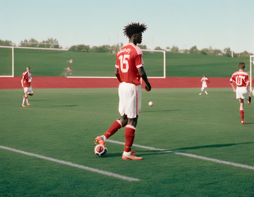 Soccer player with unique hair in red jersey on field with teammates