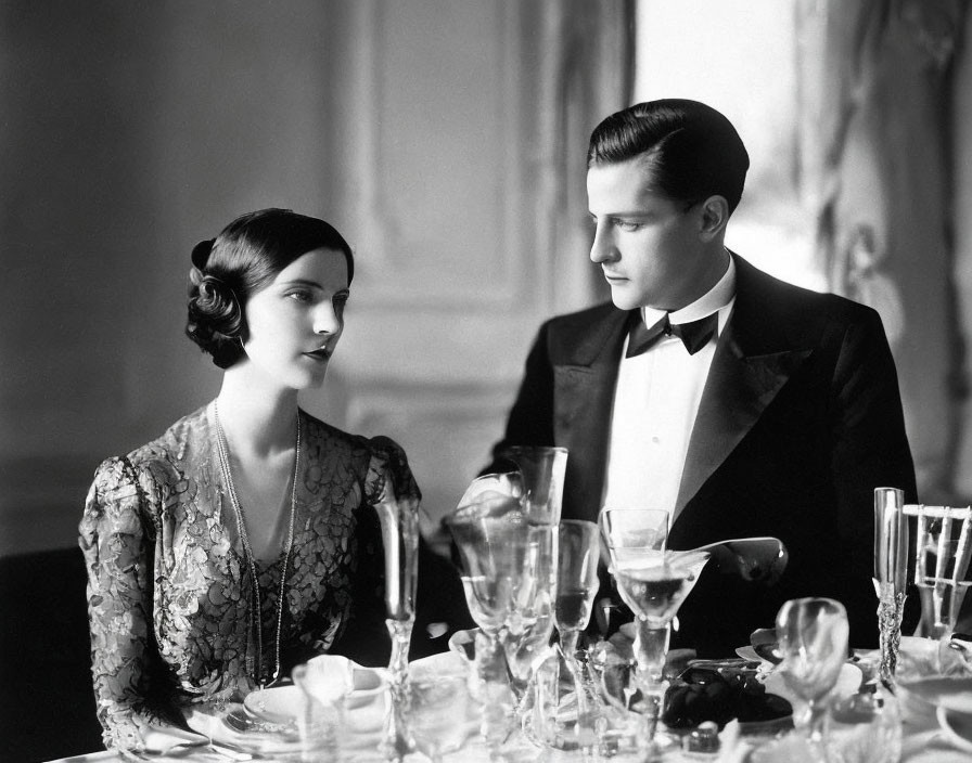 Vintage black-and-white photo: elegantly dressed couple at formal dining table