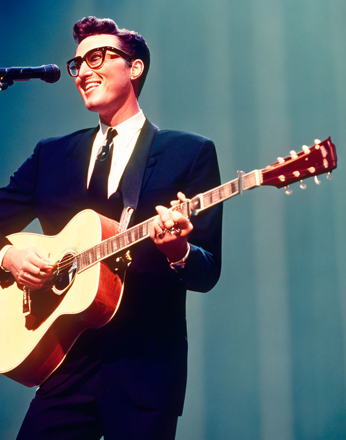 Man in suit playing acoustic guitar on stage