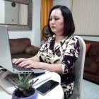 Professional woman working at organized desk with laptop, books, and smartphones.