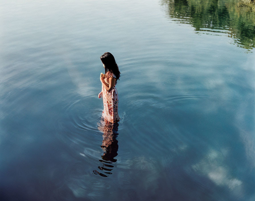 Woman in Floral Dress Standing in Tranquil Water Reflecting Serene Blue Expanse