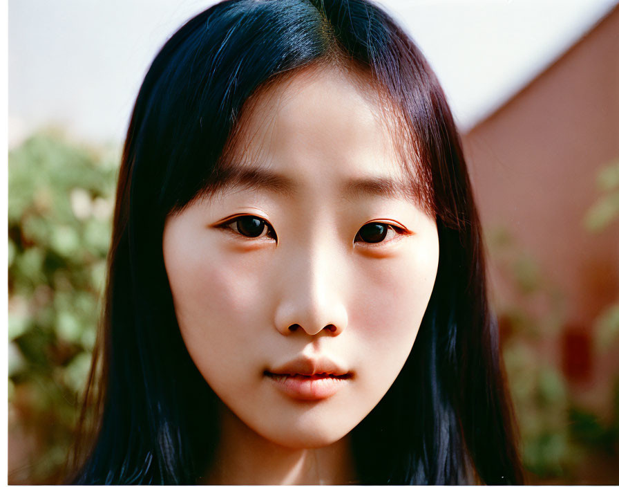 Young Asian female with dark hair in close-up portrait against blurred background