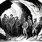 Nine 19th-Century Men in Formal Attire Inside Large Cave