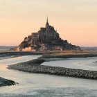 Majestic castle on cliff with stone bridge over river at sunrise