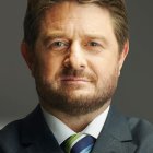 Elderly man with grey beard in brown suit and white hair