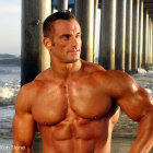 Muscular man with styled hair posing under pier by the ocean