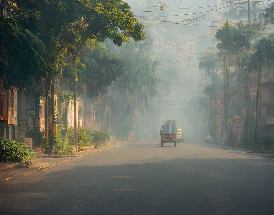 Quiet street scene with vehicle driving through morning mist and power lines overhead