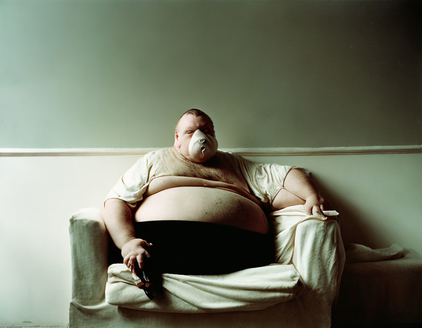 Person on Cream-Colored Sofa with Remote and Nasal Breathing Aid