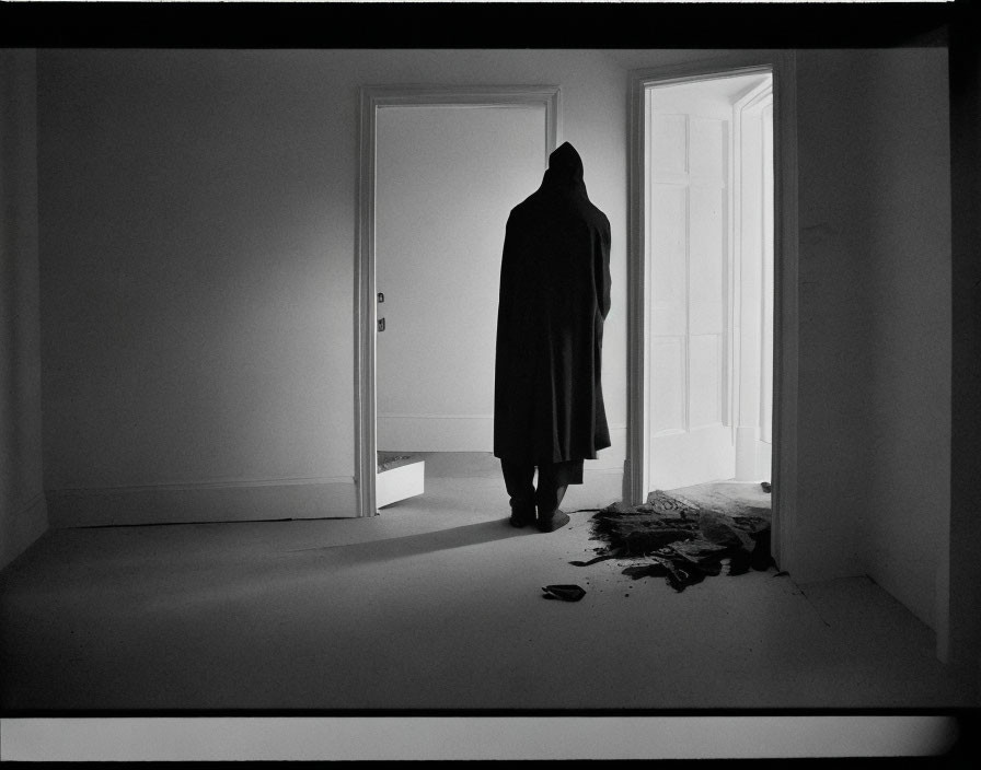 Coat hanging on doorframe in dimly lit room with scattered rug and hat