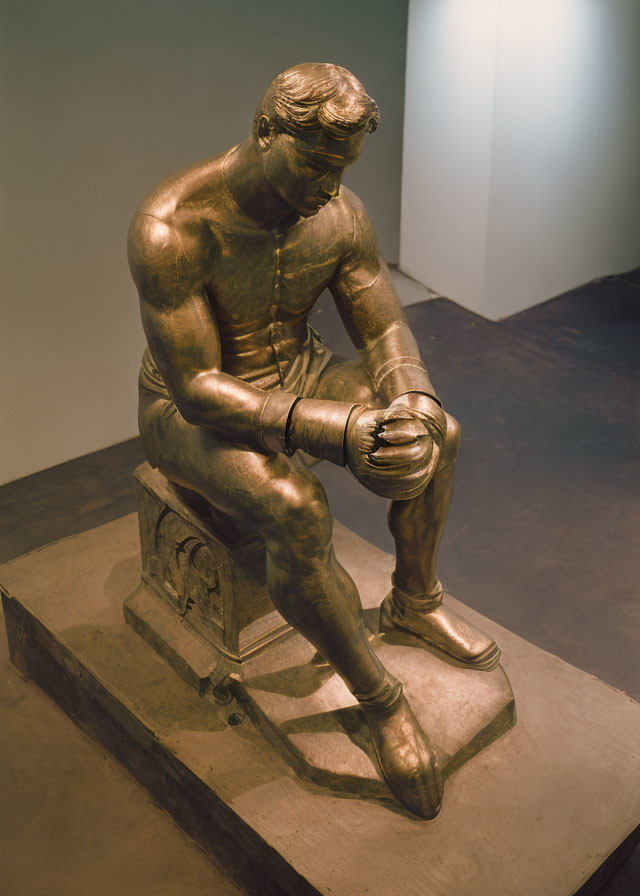 Bronze sculpture of seated contemplative man with golden patina