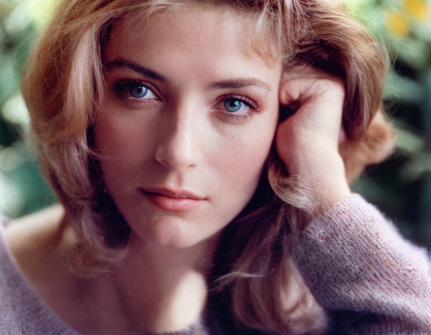 Blonde Woman with Blue Eyes Resting Chin on Hand in Close-Up Portrait