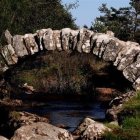 Tranquil stream with old stone bridge and lush surroundings