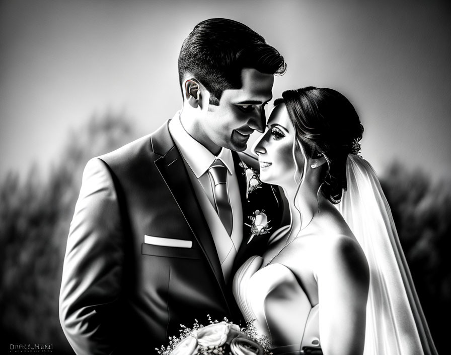 Monochrome wedding portrait of bride and groom gazing lovingly.