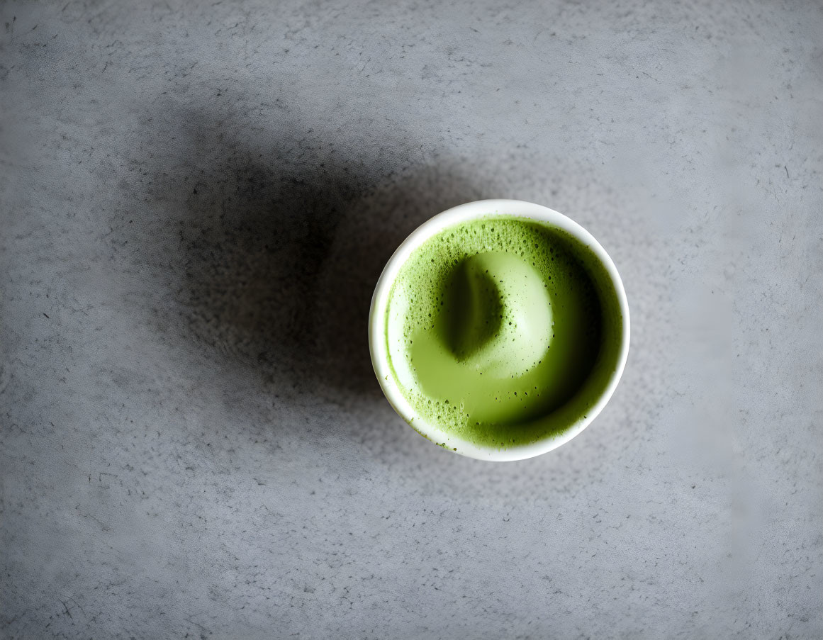 Matcha Latte Cup with Swirly Froth on Grey Surface