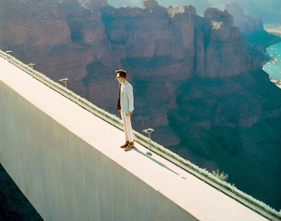 Person in Light Suit Walking on Narrow Ledge with Dramatic Canyon Backdrop