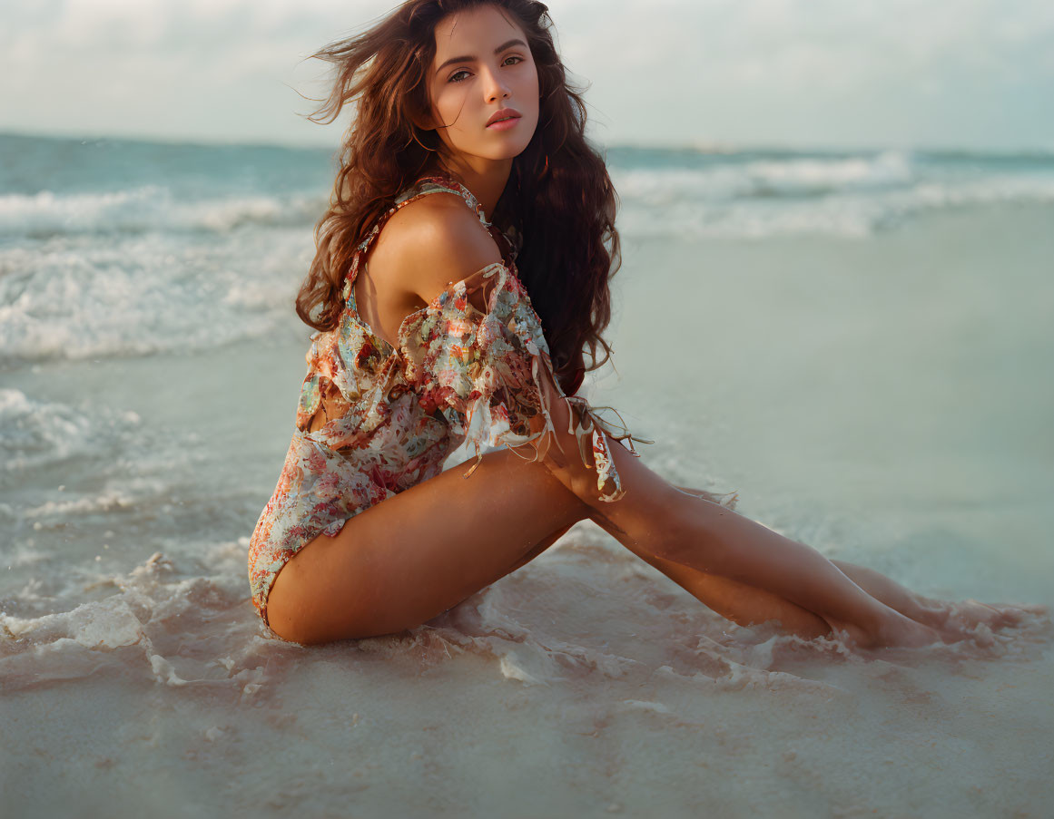 Woman in Floral Dress Sitting on Beach with Waves in Background