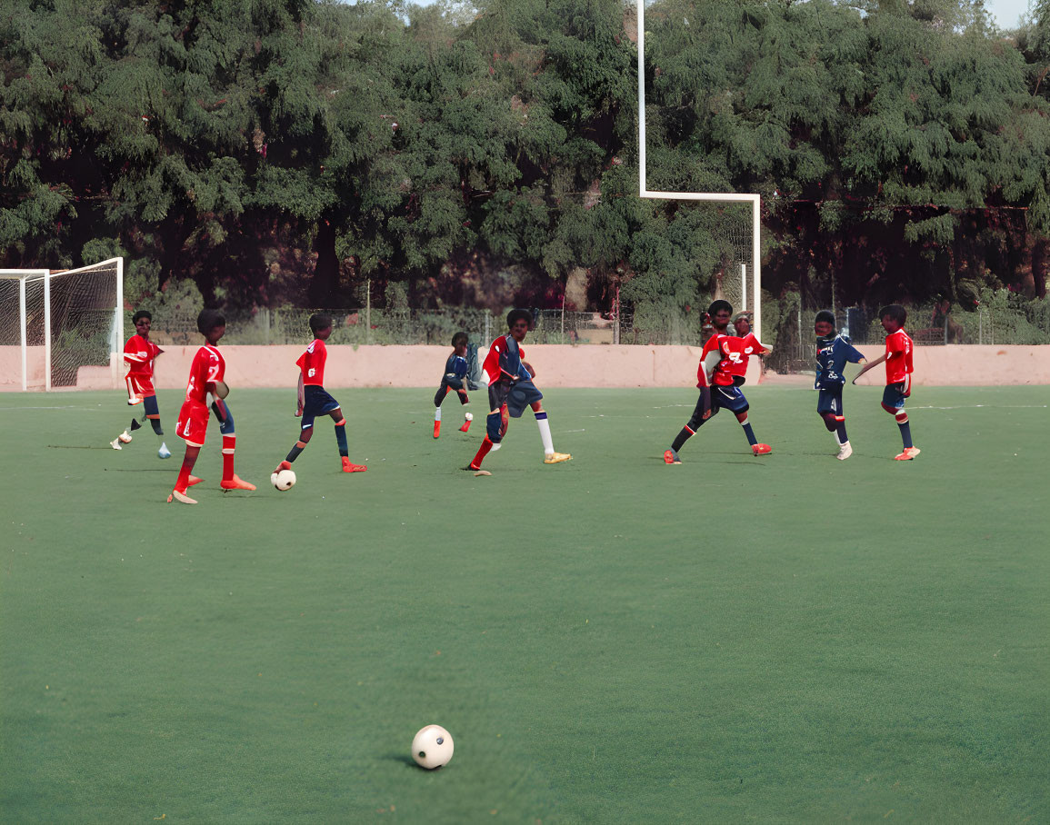 Kids playing soccer on green field with red and blue jerseys