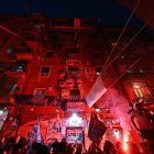 Crowd of fans waving flags with red lighting at sports event