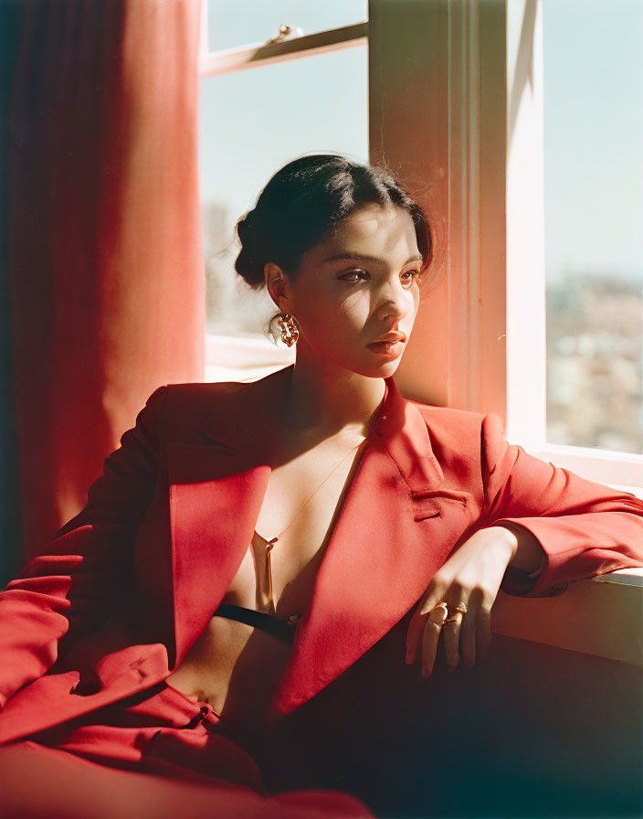 Woman in Red Suit Contemplates by Sunlit Window