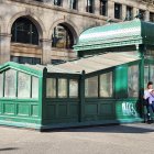 Vintage Green Subway Entrance with Frosted Glass and People on Sunny Day