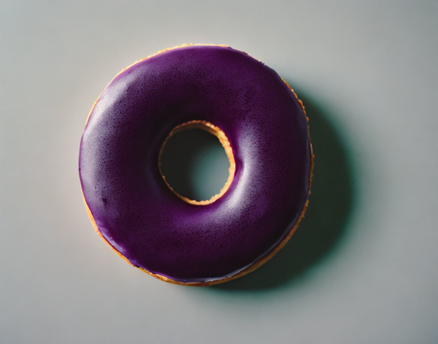 Purple-Glazed Donut on Light Grey Surface with Soft Shadow