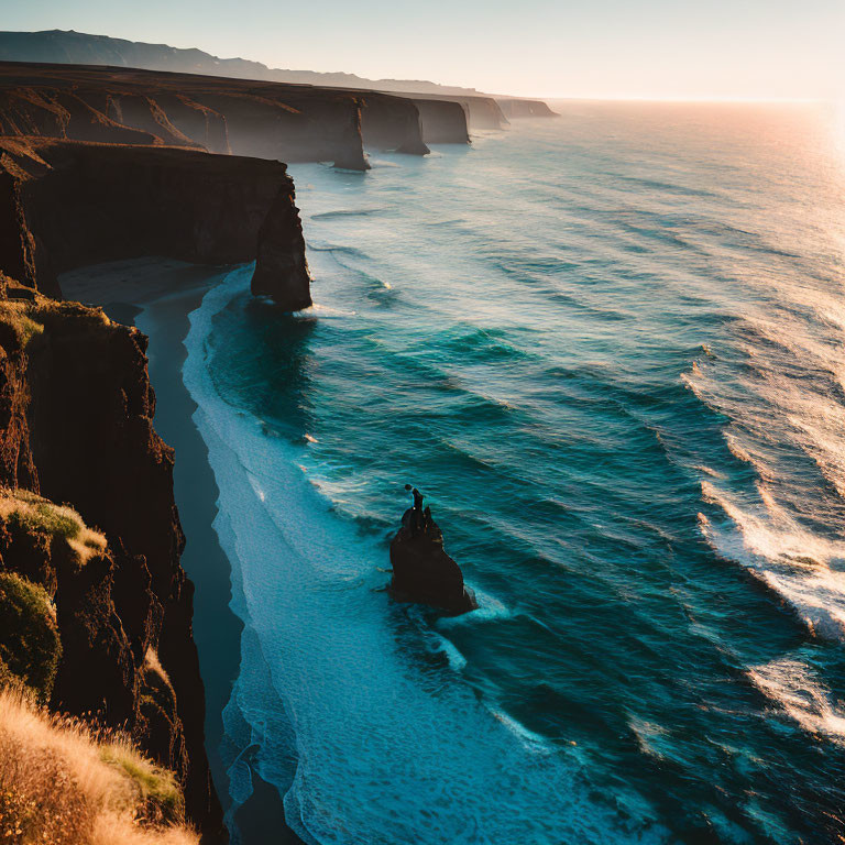 Figure on Cliff Edge Overlooking Sunset Coastline