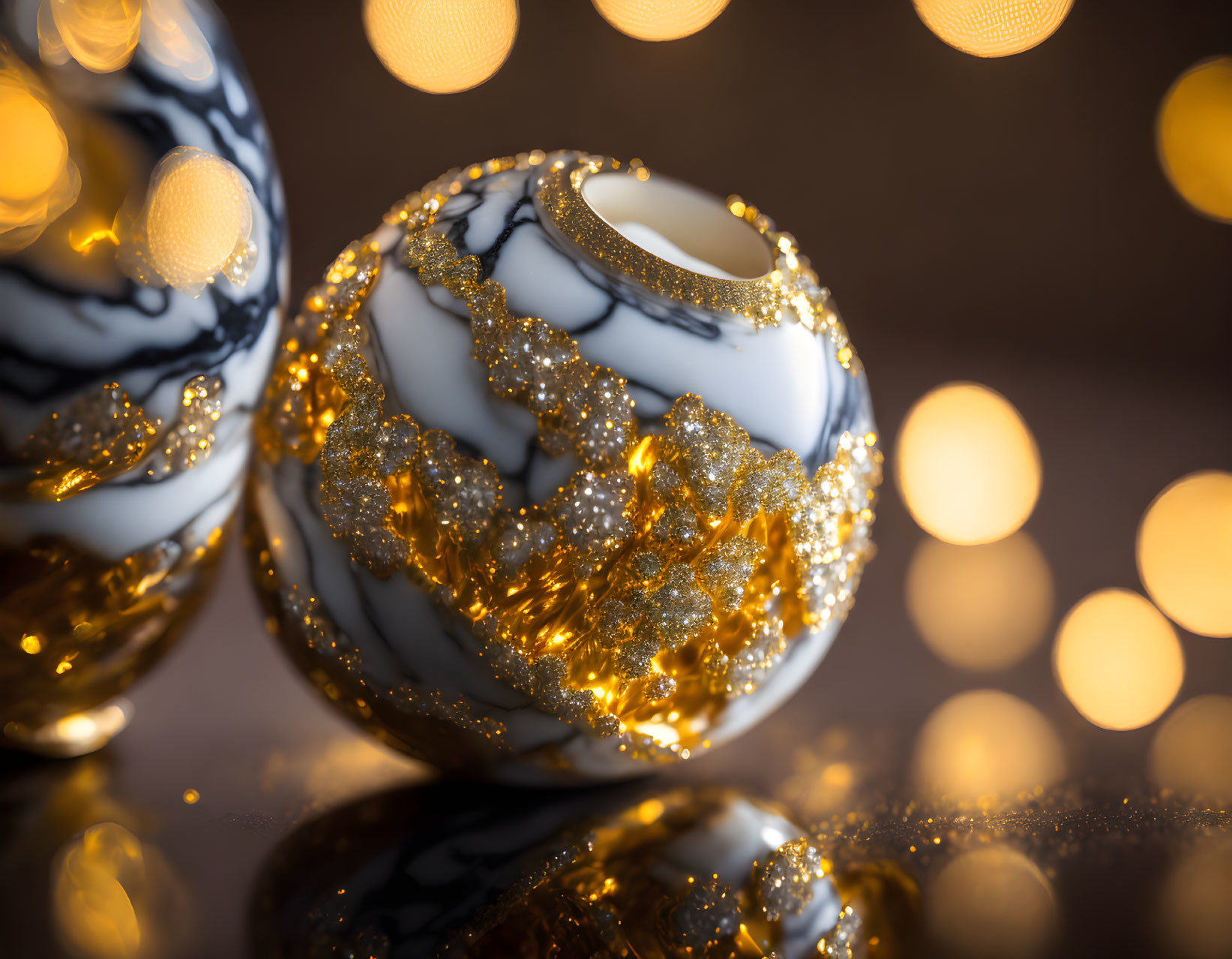 Marble-patterned black and white spheres with golden glitter on soft bokeh background