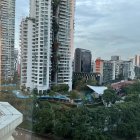 Cityscape with high-rise buildings and greenery under cloudy sky