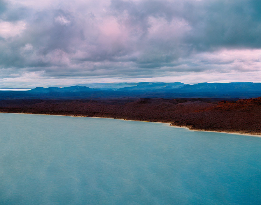 Tranquil turquoise lake, volcanic rocks, flatlands, purple-tinted clouds