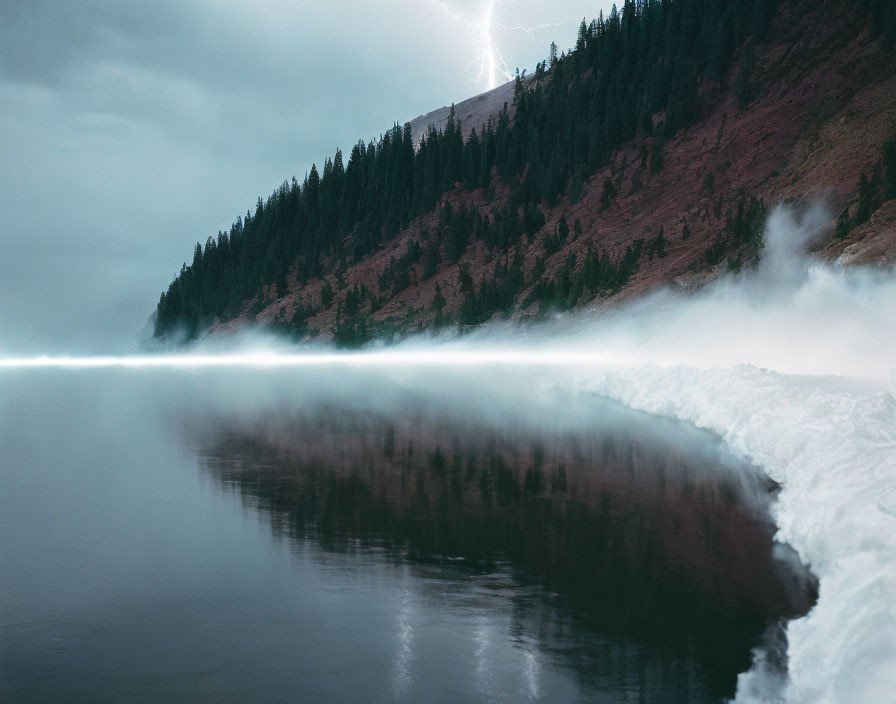 Misty lake with tree reflection, snow bank, stormy sky & lightning.