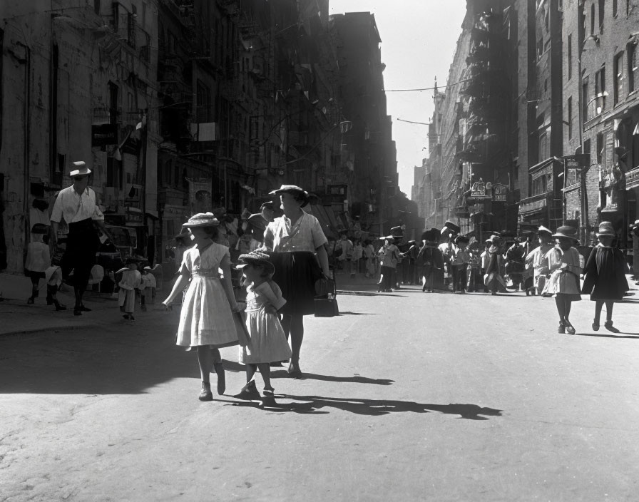 Vintage black and white photo: Three children crossing busy street with brick buildings and early 20th-century