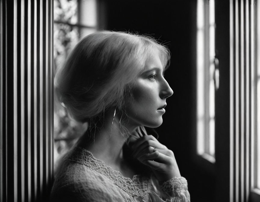 Monochrome profile portrait of woman by window with striped shadows