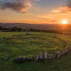 Tranquil sunset landscape with ancient stone ruin and vibrant green grass