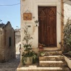 Old house with red door, stone steps, greenery, and purple flowers