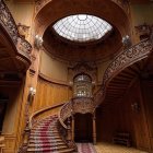 Grand vintage interior with ornate spiral staircase, dome skylight, vines, and purple petals.