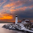 Serene lighthouse on rocky promontory at sunset