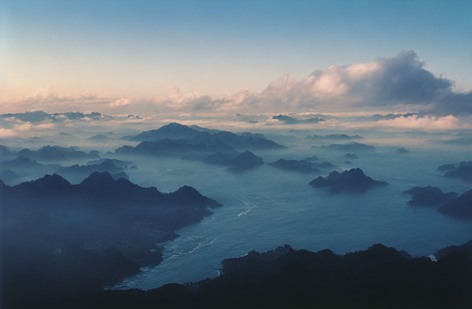 Mountain Range Covered in Mist with River and Cloudy Sky at Dusk