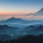 Mountain Range Covered in Mist with River and Cloudy Sky at Dusk