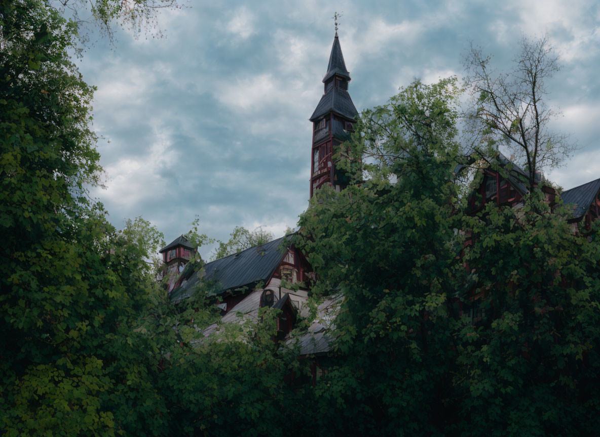 Historic church with spire nestled among trees under cloudy sky