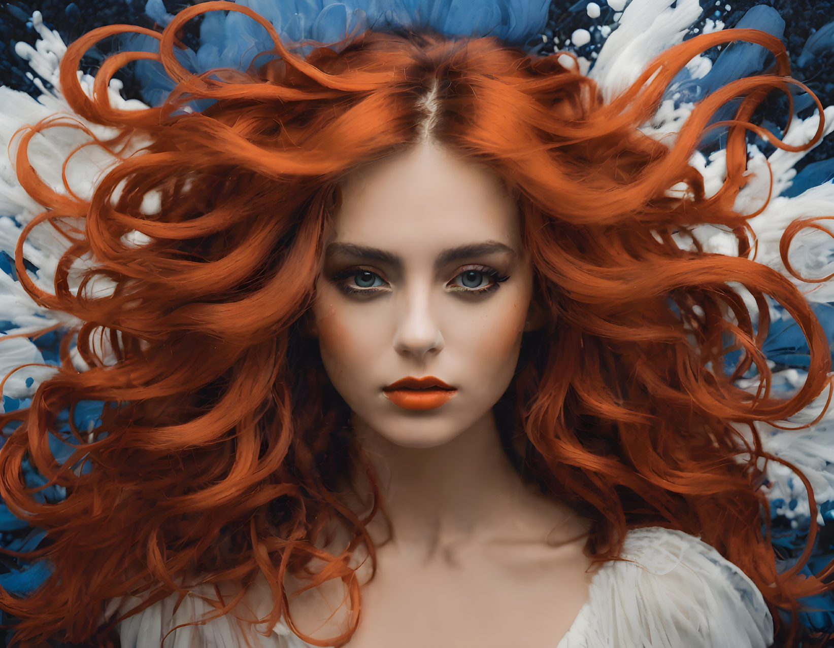 Voluminous red hair woman with striking makeup on blue floral background