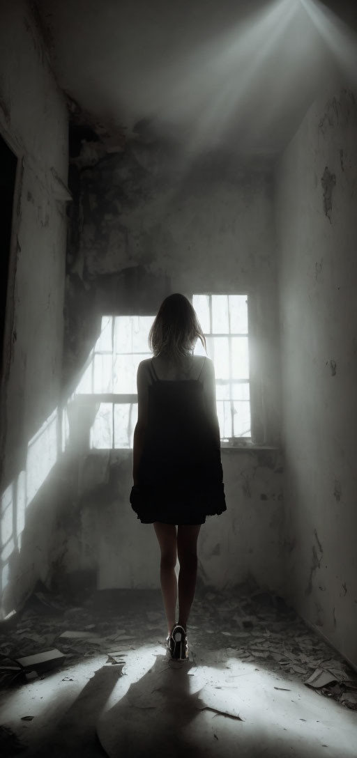 Silhouette of woman in dilapidated hallway with dramatic light beam