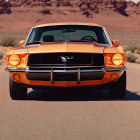 Vintage orange Mustang on empty desert road with rocky backdrop