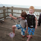 Two beached whales with young boy and seagull by pier