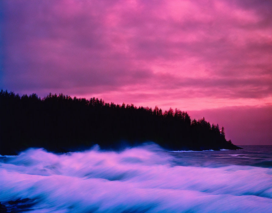 Colorful Coastal Sunset with Silhouetted Forested Shoreline