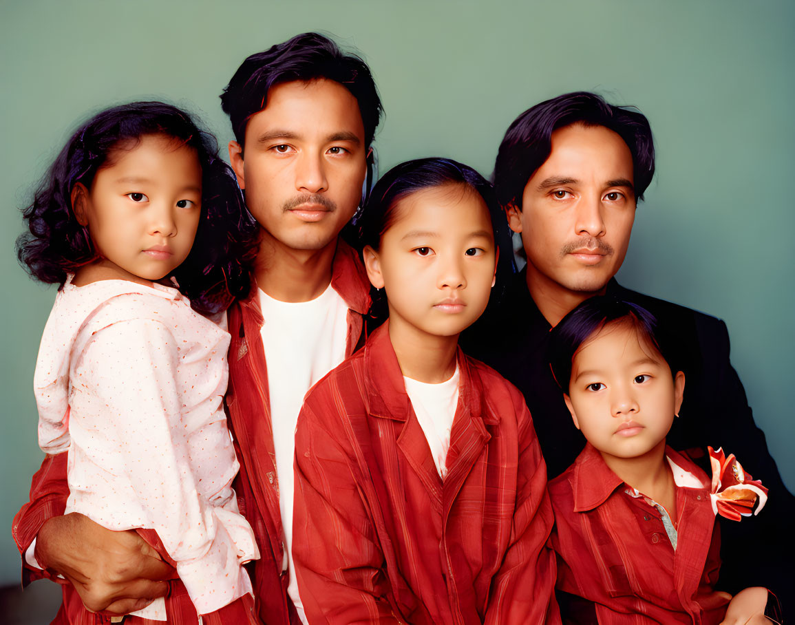 Family Portrait: Two Adults, Three Children in Red Outfits on Green Background