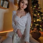 Illustrated woman in white lace dress with jewelry by Christmas tree and gifts