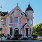 Victorian-style house with blue siding, white trim, round towers, wraparound porch, evening lighting